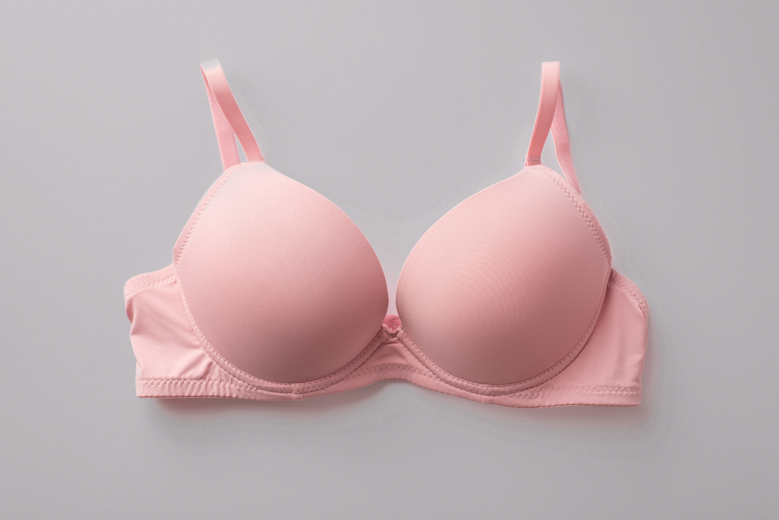 A pink bra, flat lay on a light gray background